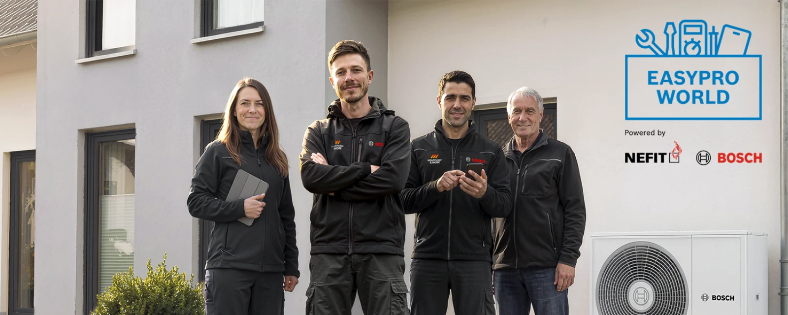 Two Bosch installers are standing next to the Compress 5800i AW heat pump.