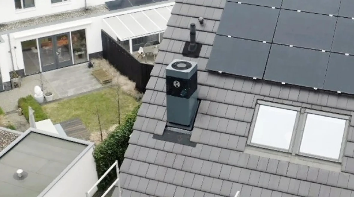 Warmtepomp met buitenunit op schuin dak naast zonnepanelen